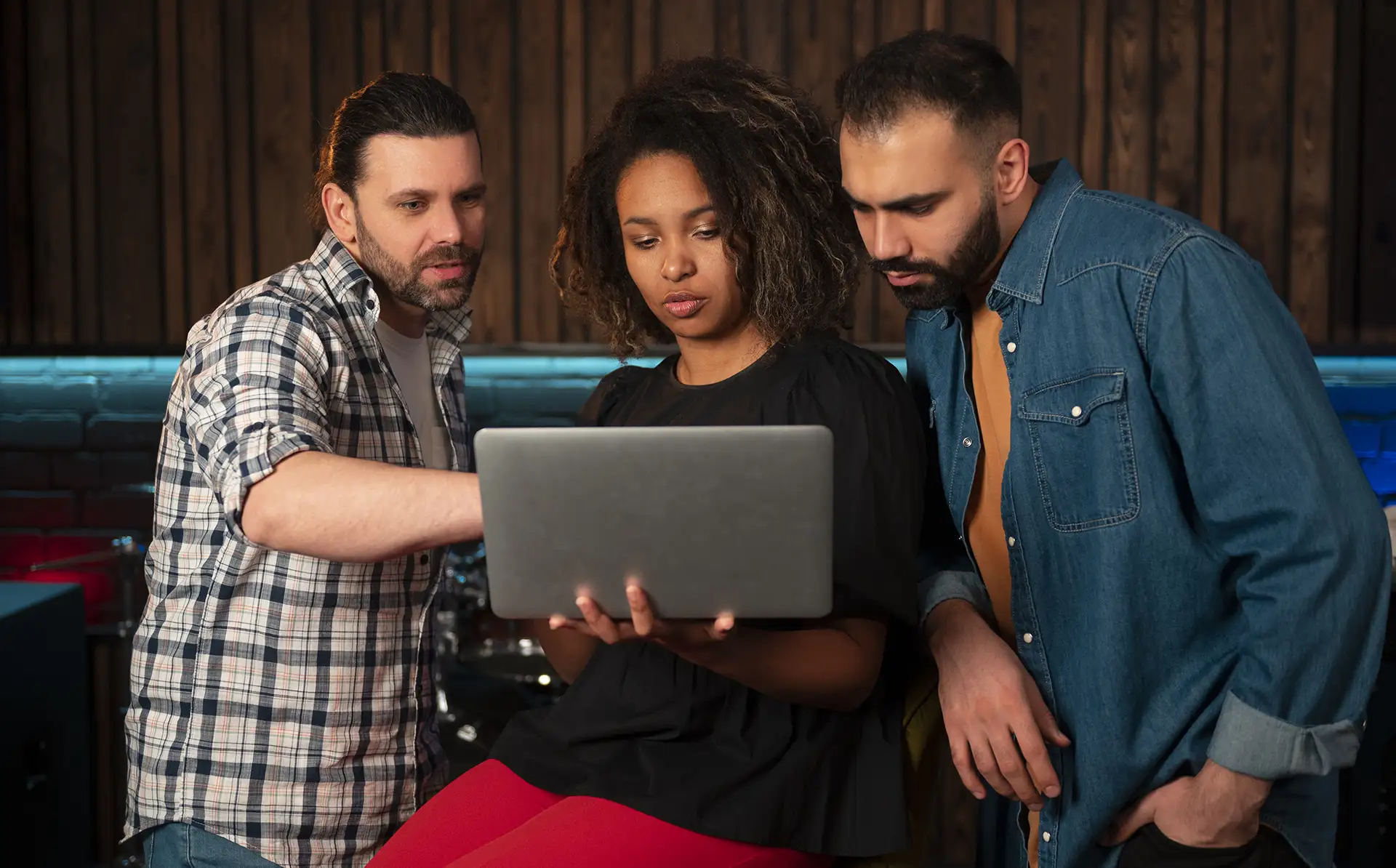 Três pessoas adultas olhando atentamente para um site com boas práticas em um notebook; dois homens brancos e uma mulher negra.